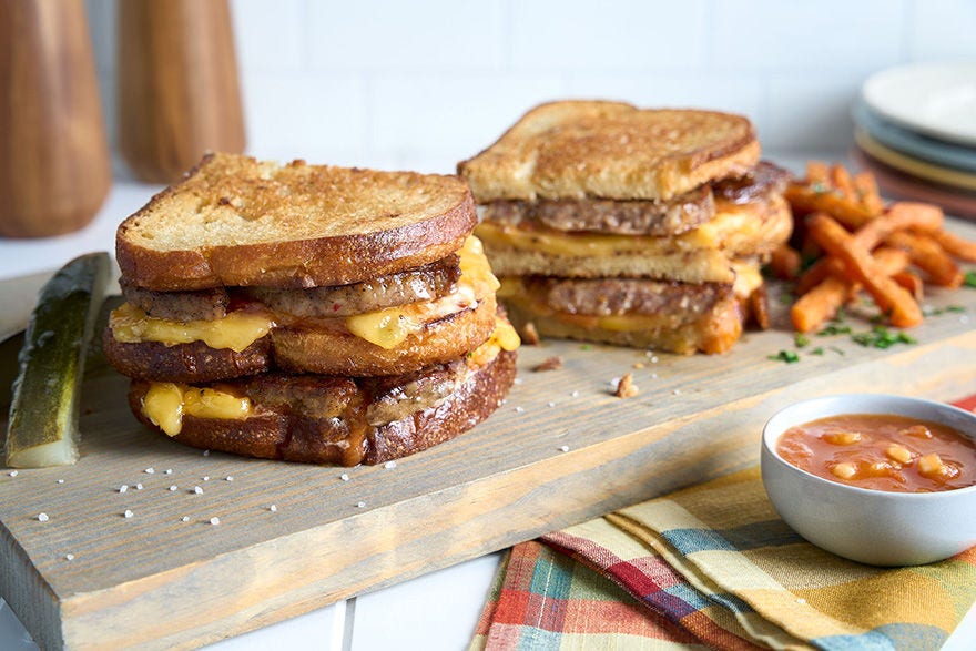 Two grilled cheese dagwoods on a serving tray with a side of fires and a pickle